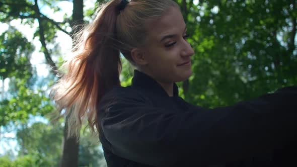 Slow motion. Happy young woman taking selfie photo with smartphone in the park. Profile view.