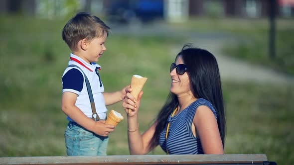 Mother and Child Eating Ice Cream Outdoors in Summer Day