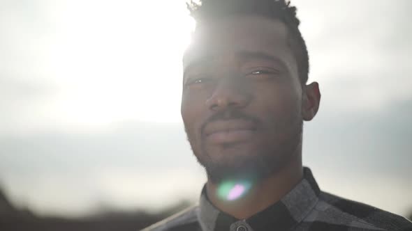 Portrait of Handsome African American Man Looking Into the Camera Outdoors. The Sunny Light Sky