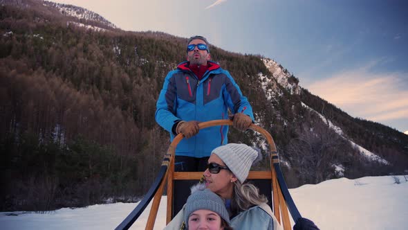 A cute young girl and her mother dogsledding through the snow with epic winter mountain peaks in the