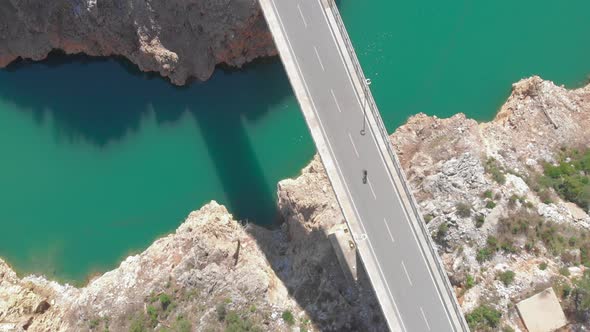 Person rides bicycle on bridge over river