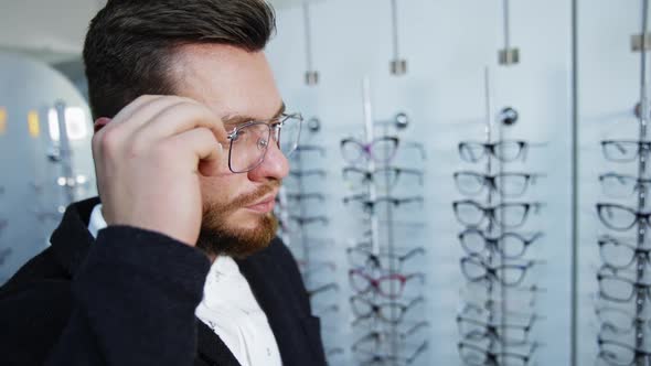 Patient in optics store. Male patient with new eyeglasses in store