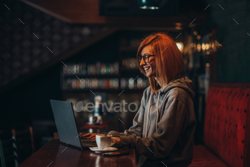 Busy redhead woman working on her laptop in a cafe