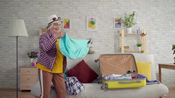 Positive Old Woman Packing Her Suitcase for Travel