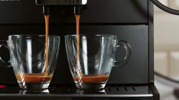 Brewed Coffee Is Poured From the Coffee Machine Into Glass Cups