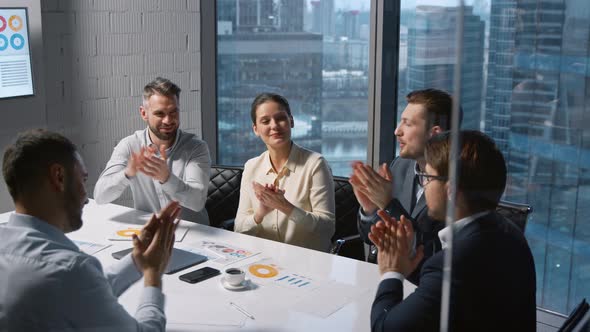 Applauding team of professionals after the completion of negotiations in a modern office