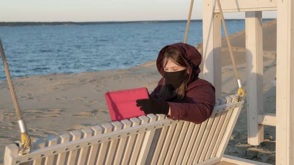 Girl in a Mask Outdoors Uses a Tablet. Insulation