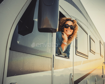 oung woman outside the driver window of modern camper van mothr home vehicle. Concept of travel and summer holiday vacation and destination people