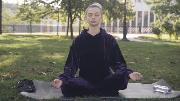 Wide Shot of Calm Confident Caucasian Woman Sitting in Lotus Pose on Exercise Mat