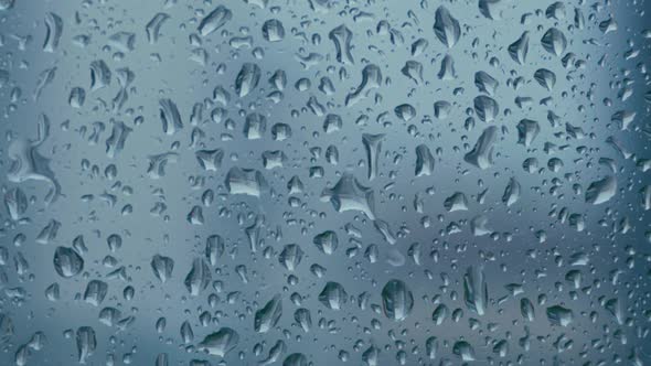 Large Rain Drops Strike a Window Pane During a Summer Shower