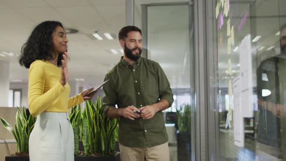 Video of happy diverse businesswoman and businessman brainstorming in office
