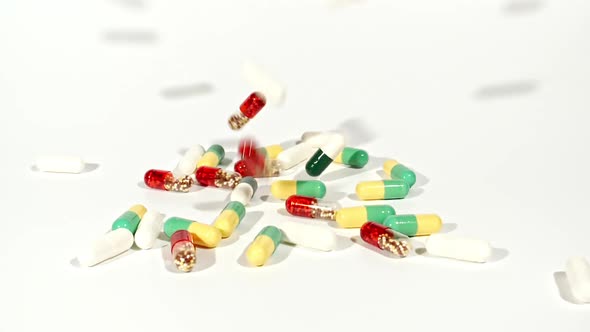 Closeup of Different Medical Pills Falling on Table on White Background