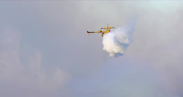 The Aerial View of a Water-bomber Dumping the Water and Disappearing in a Smoky Sky.