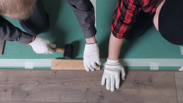 Two Workers are Laying Laminate Flooring in a Small Apartment