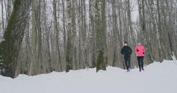 Man and Woman Run in the Park in Winter in Slow Motion