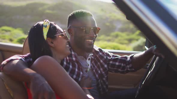 African american couple talking to each other while sitting in convertible car on road