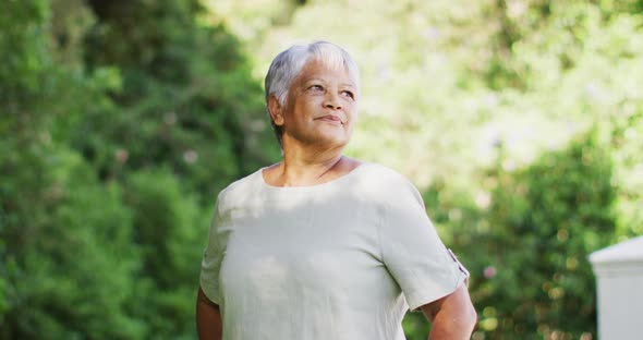 Video of happy biracial senior woman looking at camera in garden