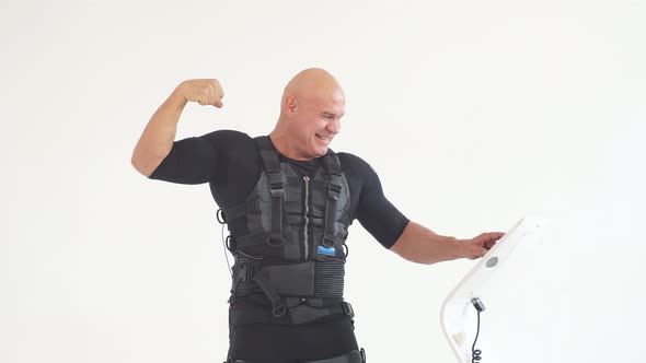 Strong Cheerful Man in EMS Suit Showing His Biceps While Training