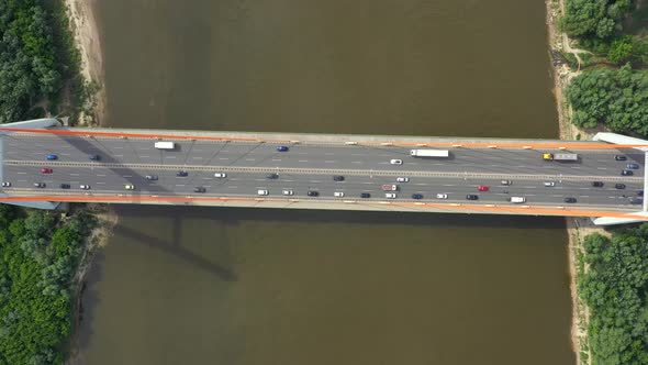 City caring at highway bridge on background smooth river surface drone view