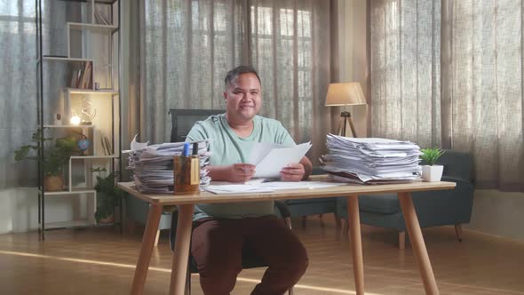 Fat Asian Man Smiling To Camera While Working With Documents At The Office