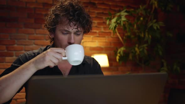 Young Successful Businessman Drinking Coffee Working in Office at Night