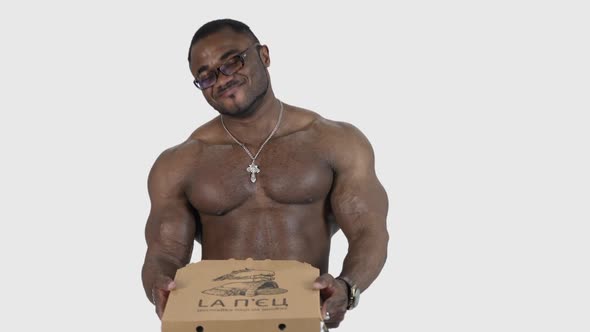 Fit man with pizza standing isolated over grey background in studio