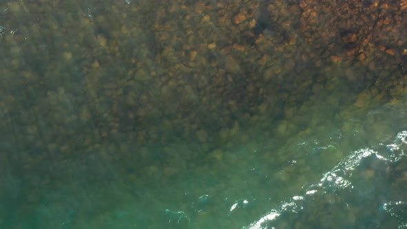 A dynamic aerial shot above the Lake Superior in Minnesota while facing downwards towards the water.