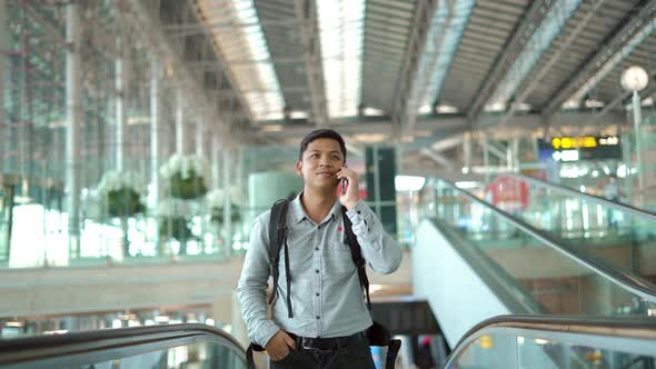 Young man  standing on the moving walkway while using smartphone.