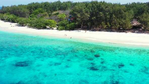 A small group of tourists enjoying a beautiful sunny day on a tropical beach paradise surrounded by