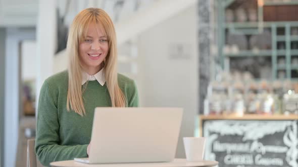 Young Woman Talking on Video Call on Laptop in Cafe