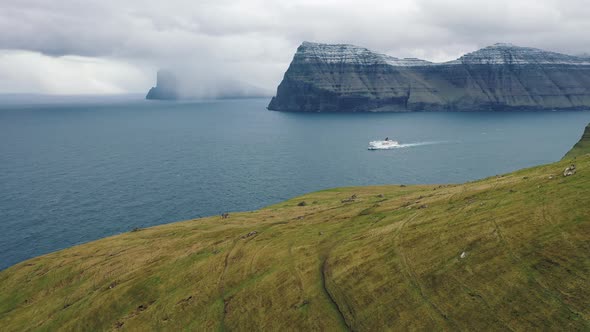 Flight Over Mountains on Faroe Islands Towards a Bay with a Cruise Ship