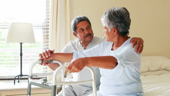 Senior man helping woman to walk with a walker 4k