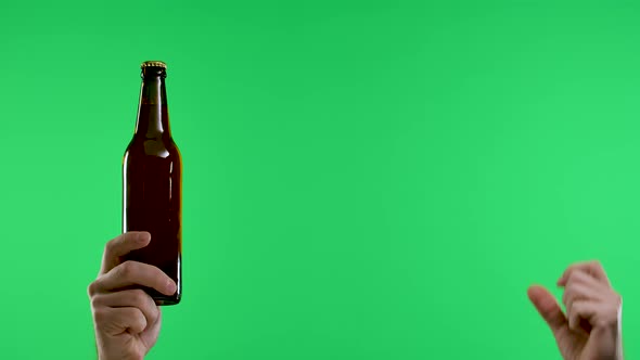 The Male Hand Points with the Index Finger to the Other Hand Holding a Dark Brown Bottle of Beer or