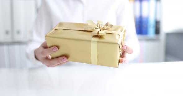 Woman Holding Golden Gift in Her Hands in Office Closeup  Movie