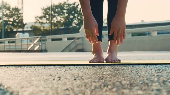 Young woman doing yoga exercise on a yoga mat at the park in summer.