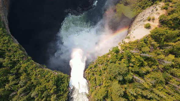 Helmcken Falls cascading over a cliff into the Murtle River with a small rainbow below in British Co