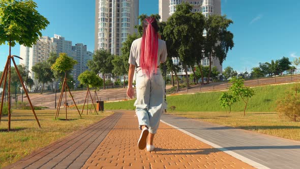 Back View Mixed Race Female Stroll Outdoors Holding Cellphone