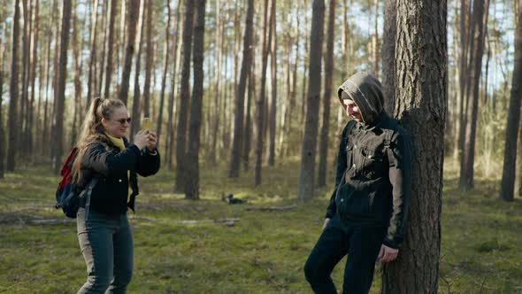 Girl Takes a Picture of a Guy on the Phone in the Forest