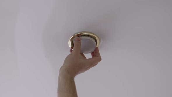A Male Electrician Changes the Light Bulbs in the Spotlight Ceiling Lamp