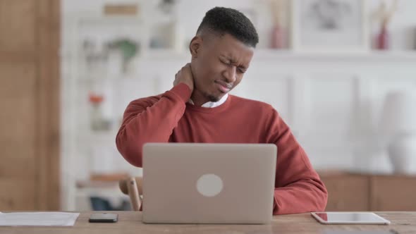 African Man having Neck Pain while using Laptop in Office