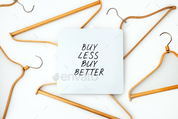 conomy, Sustainable fashion concept with wooden clothes hangers and text Buy less, buy better.