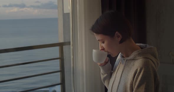 Side Portrait of Young Girl Drinking Tea and Looking Outside