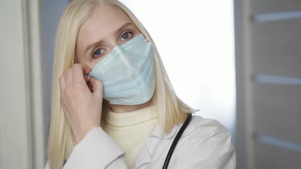 Portrait of Overworked Nurse Taking Off Face Mask During Break in Busy Hospital During Health