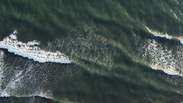 Aerial top view powerful waves on blue turquoise ocean crashing and foaming. Drone 4K footage sunny 