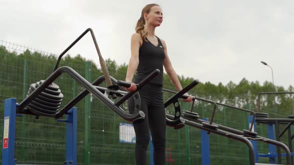 Young Fitness Woman Does a Heavy Deadlift in the Simulator at the Outdoor Sports Ground