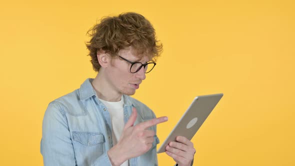 Redhead Young Man Loss on Tablet, Yellow Background 