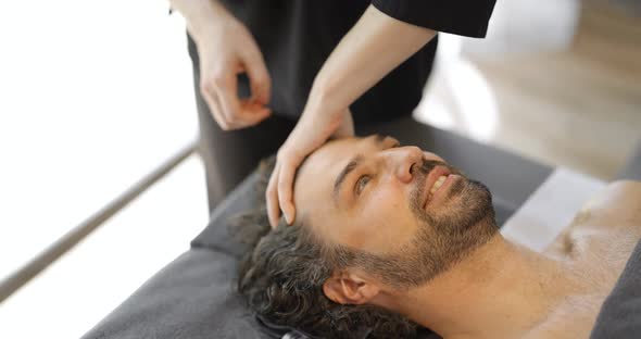 Female Masseur Doing Facial Massage to a Male Client