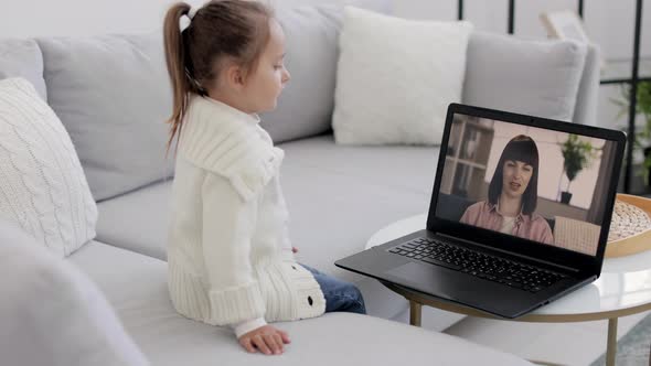 Back View of Young Girl Sitting and Relaxing on Sofa at Home and Talking on Video Call with Smiling