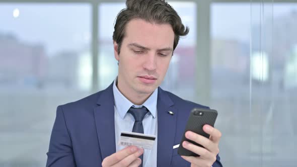 Portrait of Young Businessman Celebrating Online Payment on Smartphone 