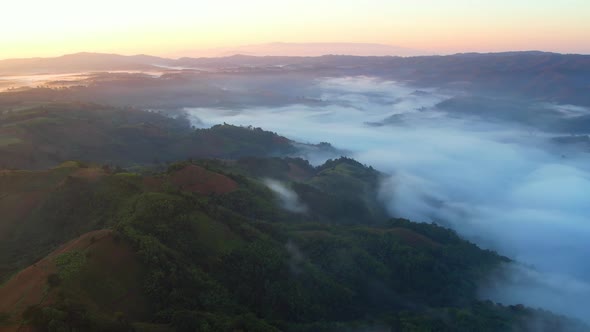 Aerial view of sunrise with fog above mountains. Golden hour and amazing sun rays